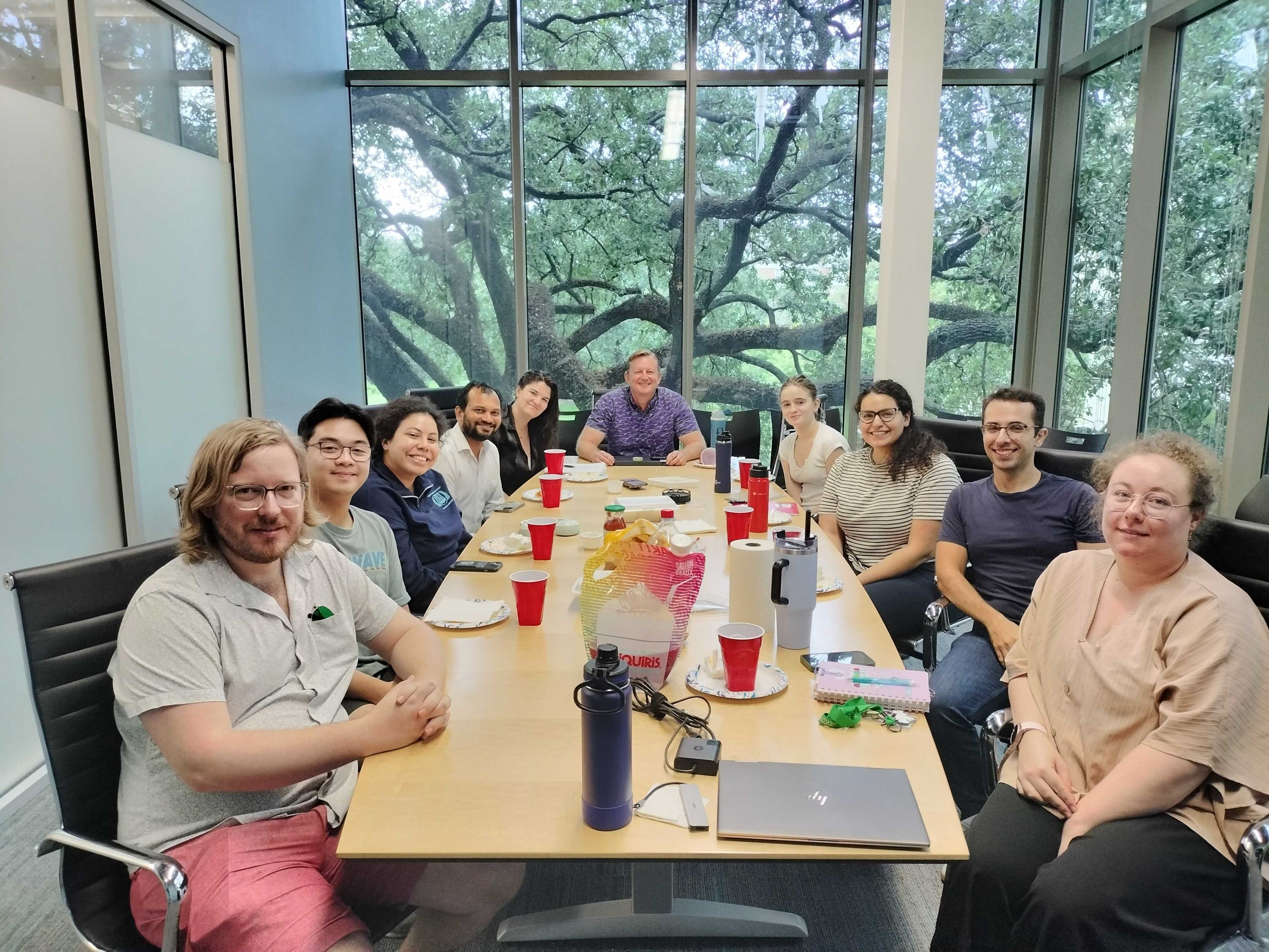 The lab sit around a table eating pizza and celebrating