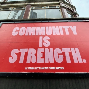 Red sign with white text: Community is Strength.