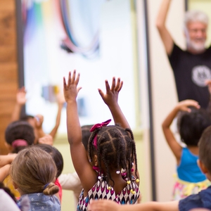 A group of children raise their hands in a classroom