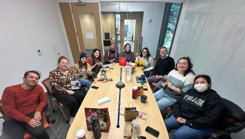 The fadok lab gathered around a table with gifts and wrapping strewn about after having a white elephant secret santa party.