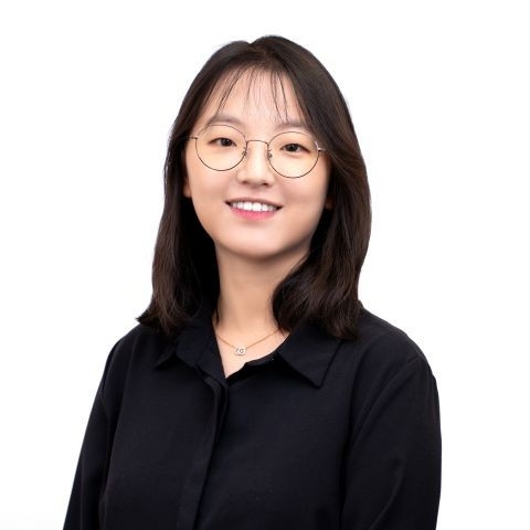 Woman with glasses and a black shirt, smiling.
