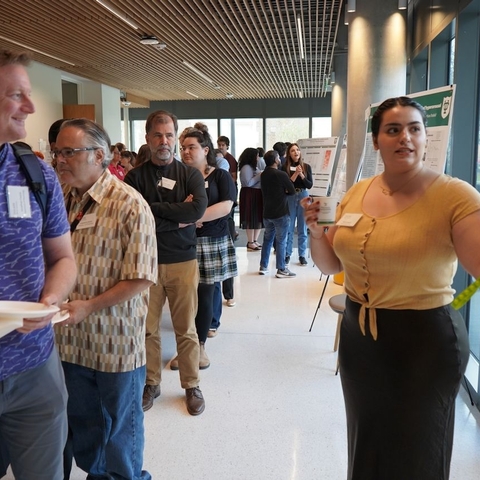 Dr. Fadok and others stand listening to Maria Najjar present in front of her poster