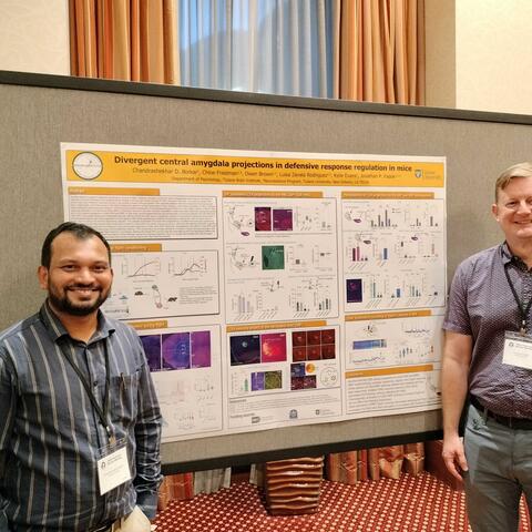 Dr. Fadok and Dr. Borkar stand in front of Dr. Borkar's poster at the Pavlovian society conference.