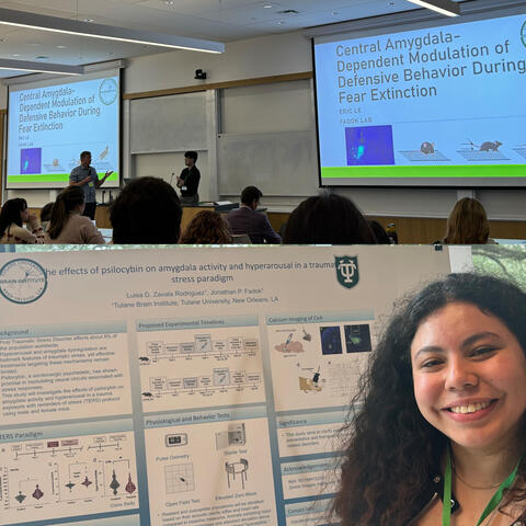 Eric is being introduced by Dr. Fadok for his presentation in the top photo and the bottom photo shows Luisa standing next to her poster and smiling.